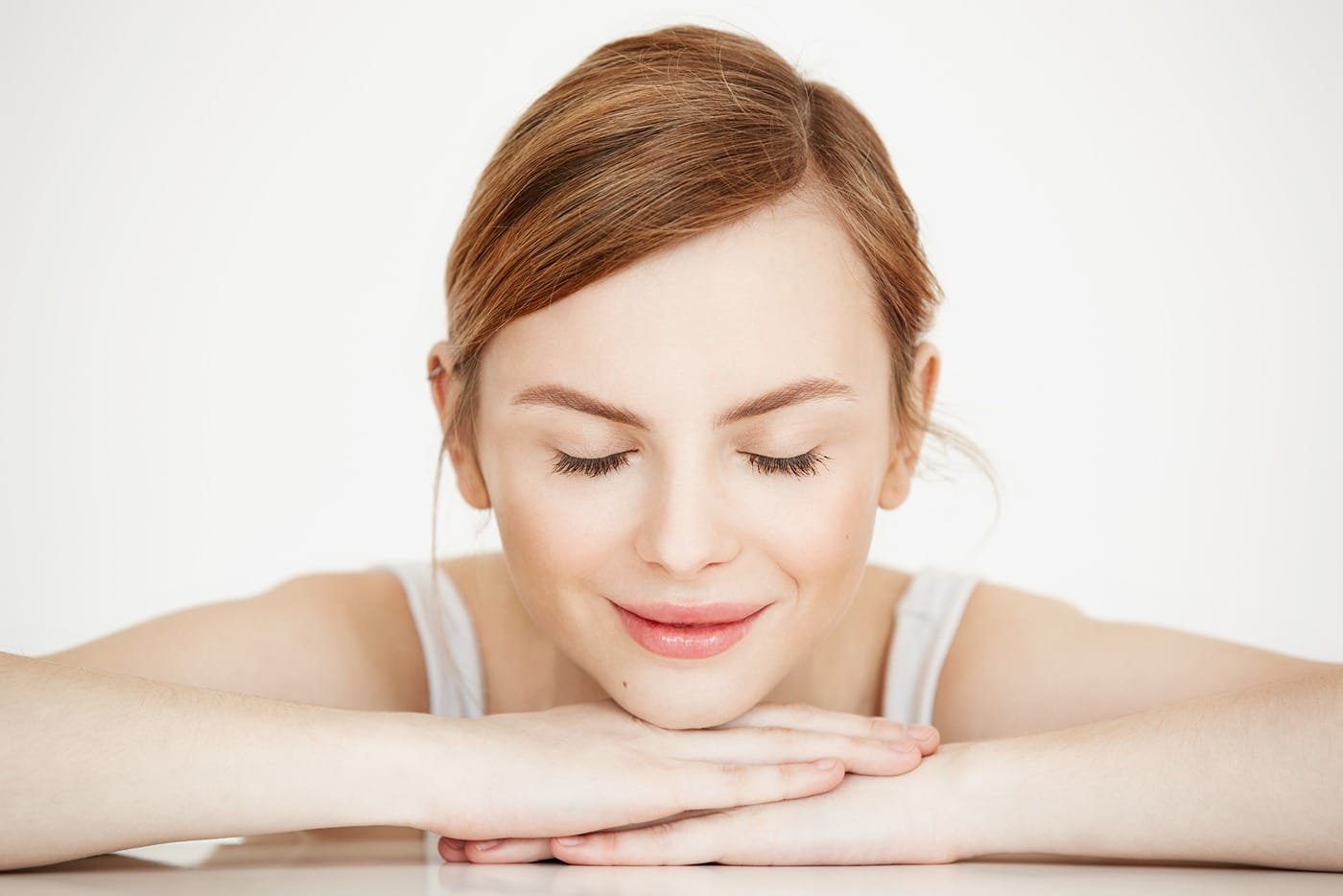 Young beautiful girl with perfect clean skin smiling with closed eyes sitting at table . Beauty spa and cosmetology.
