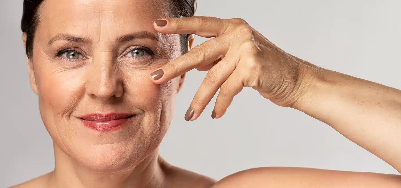 Mature woman with make-up on posing with hand on face and showing off nails